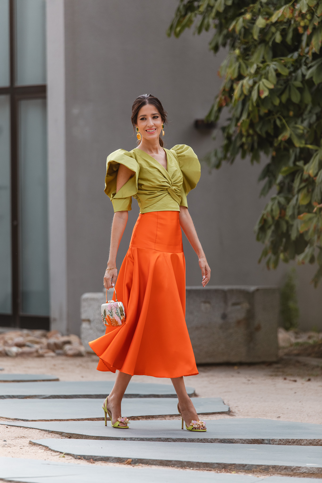 Falda naranja de vuelo y top lima con mangas abiertas, look de invitada elegante