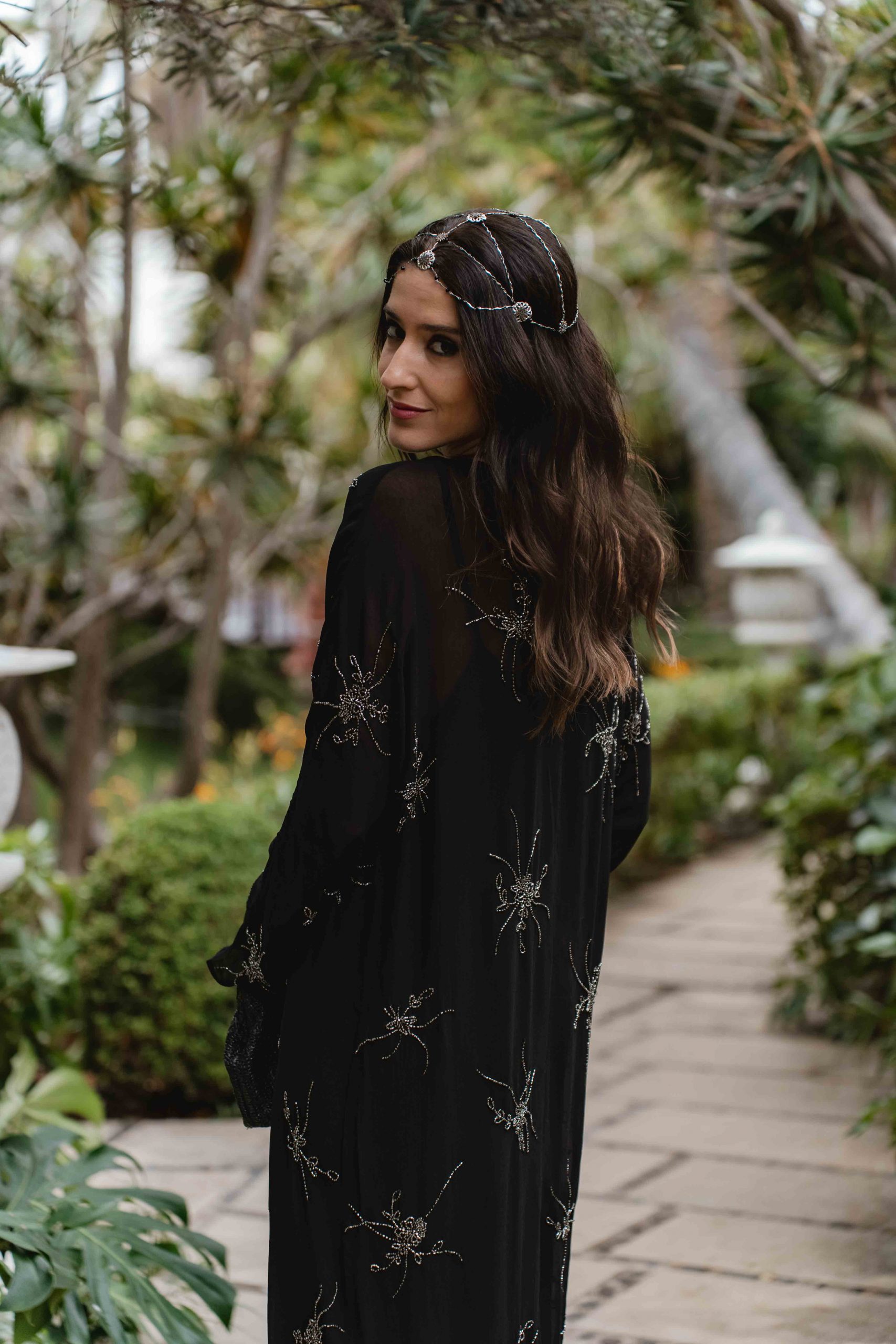 Invitada de boda boho con vestido negro bordado y tocado casquete de Cala by Lilian.
