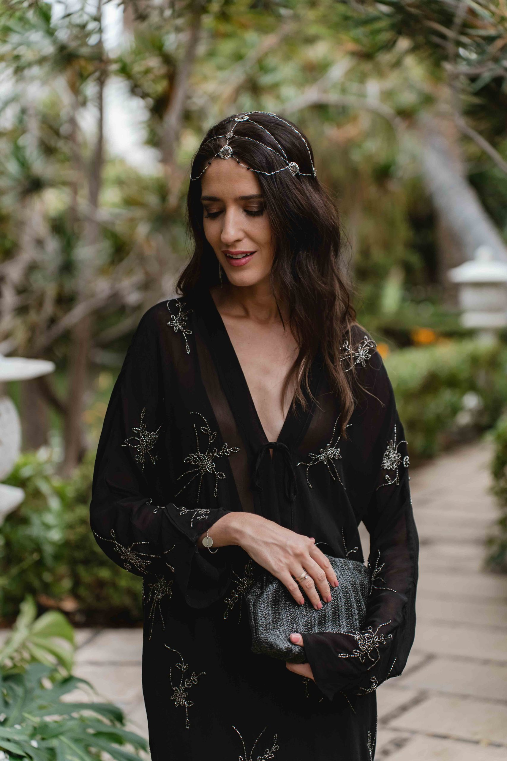 Plano medio del look de invitada con vestido bordado y complementos plateados