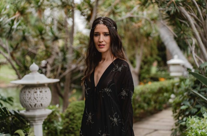 Invitada elegante con vestido negro bordado y joyas en plata, estilo boho.