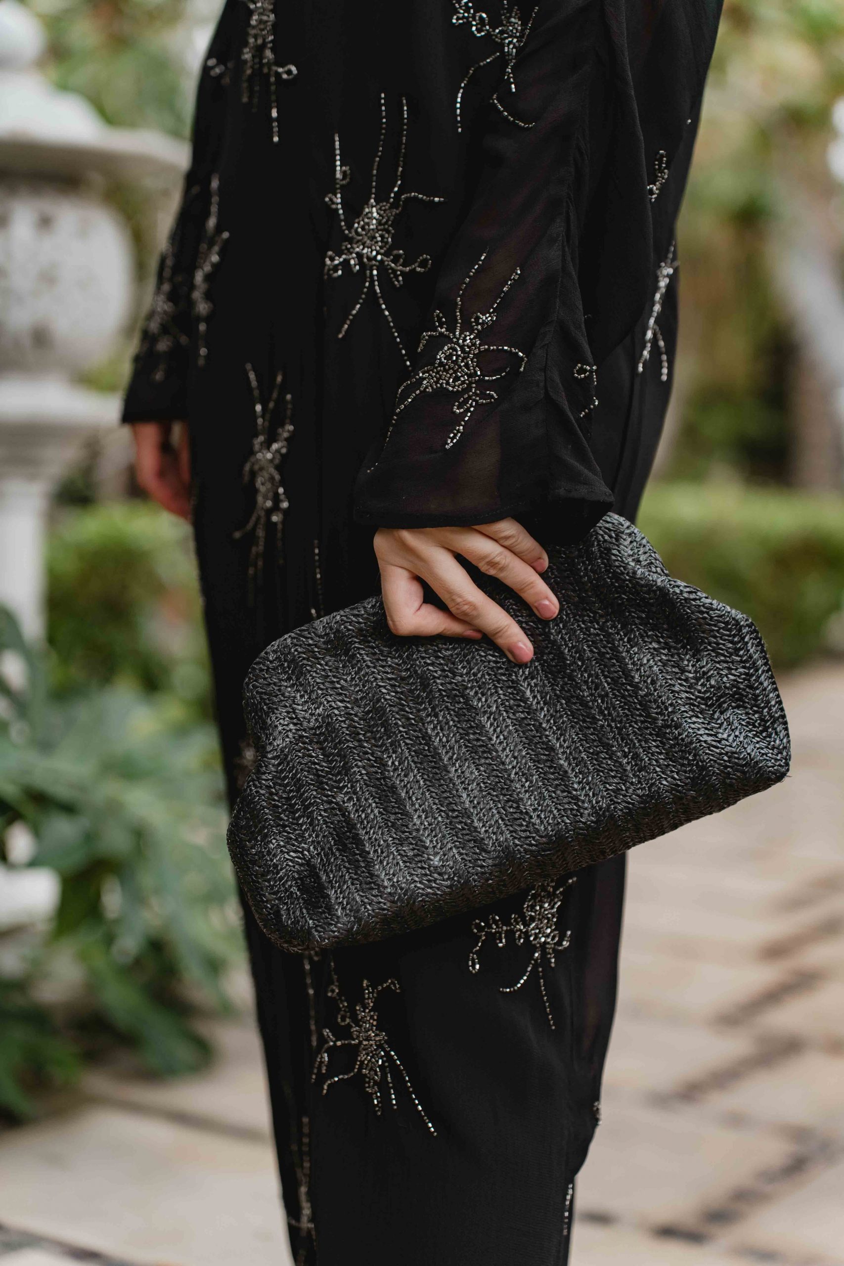 Bolso de rafia negra de Marcela and Co con sandalias plateadas de Magrit.