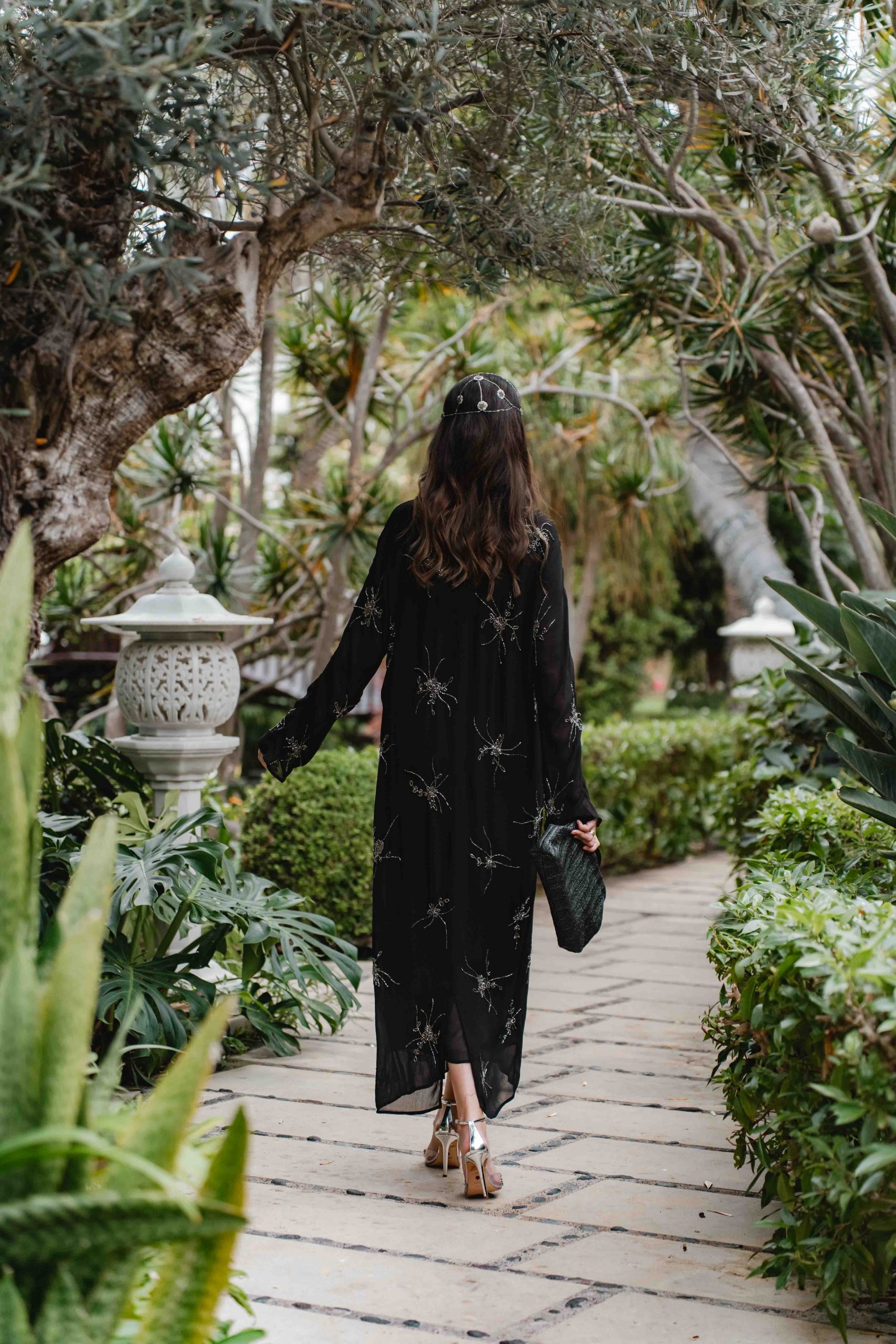 Espalda del look de invitada boho con vestido negro de Massimo Dutti con casquete