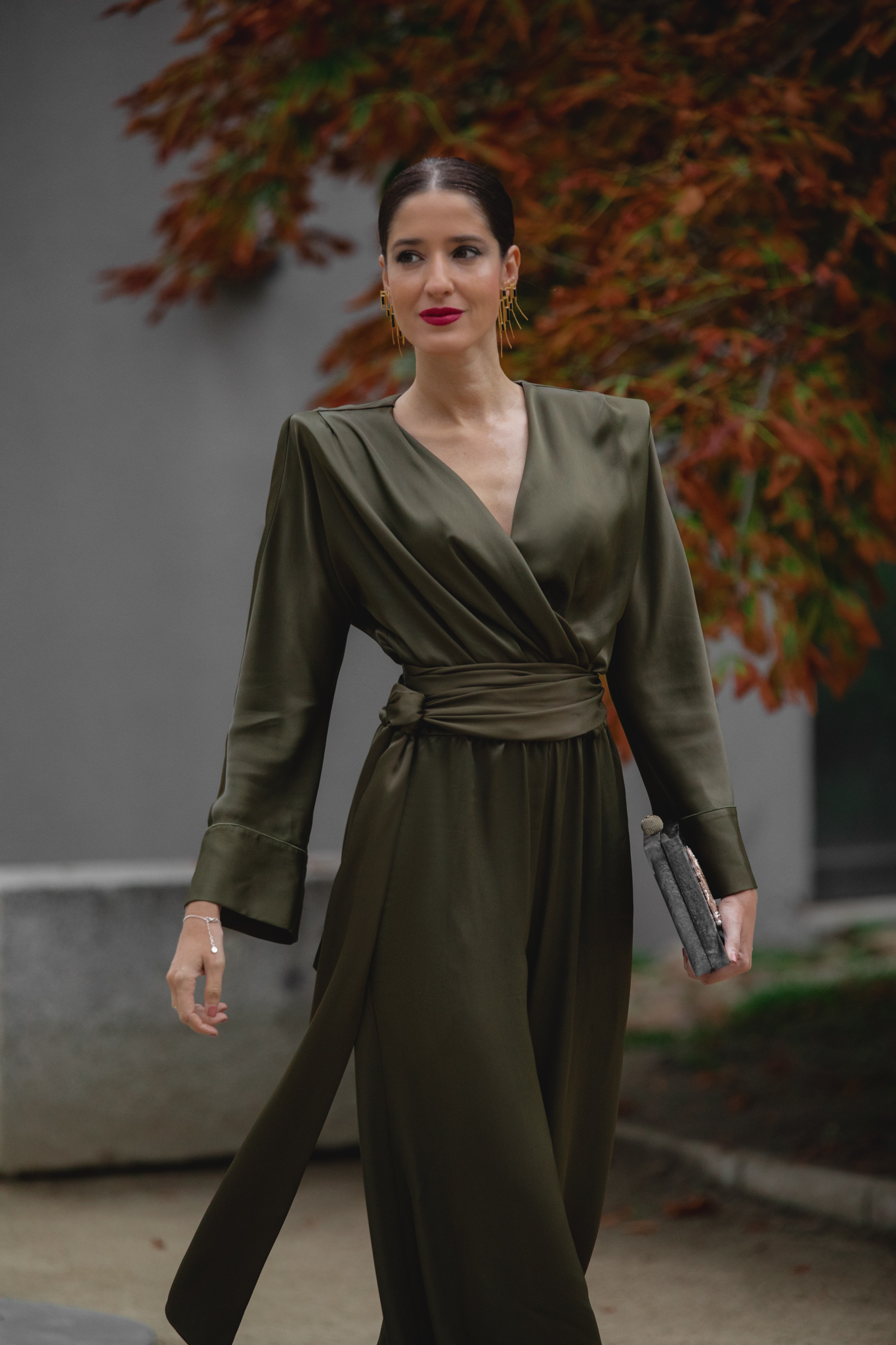 Invitada de boda de tarde con mono verde oliva y clutch negro.