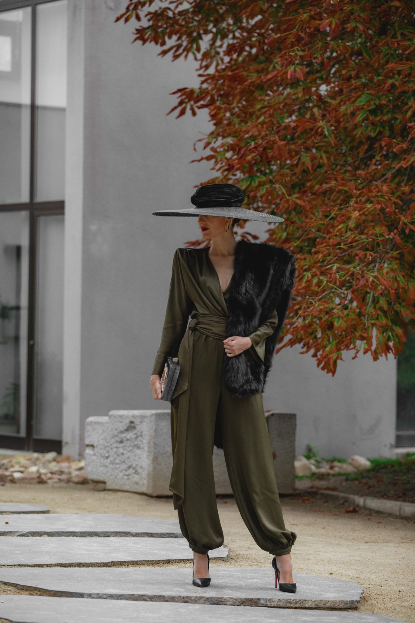 Look de boda de mañana con pamela negra y complementos dorados.