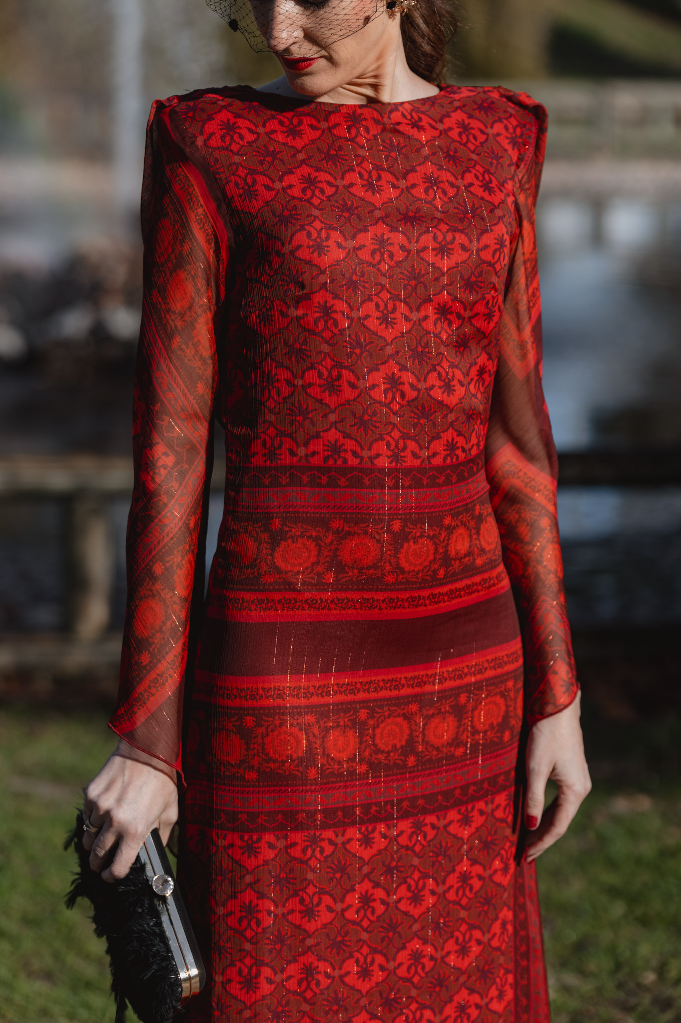 Detalle del vestido rojo de invitada de invierno con motivos granates