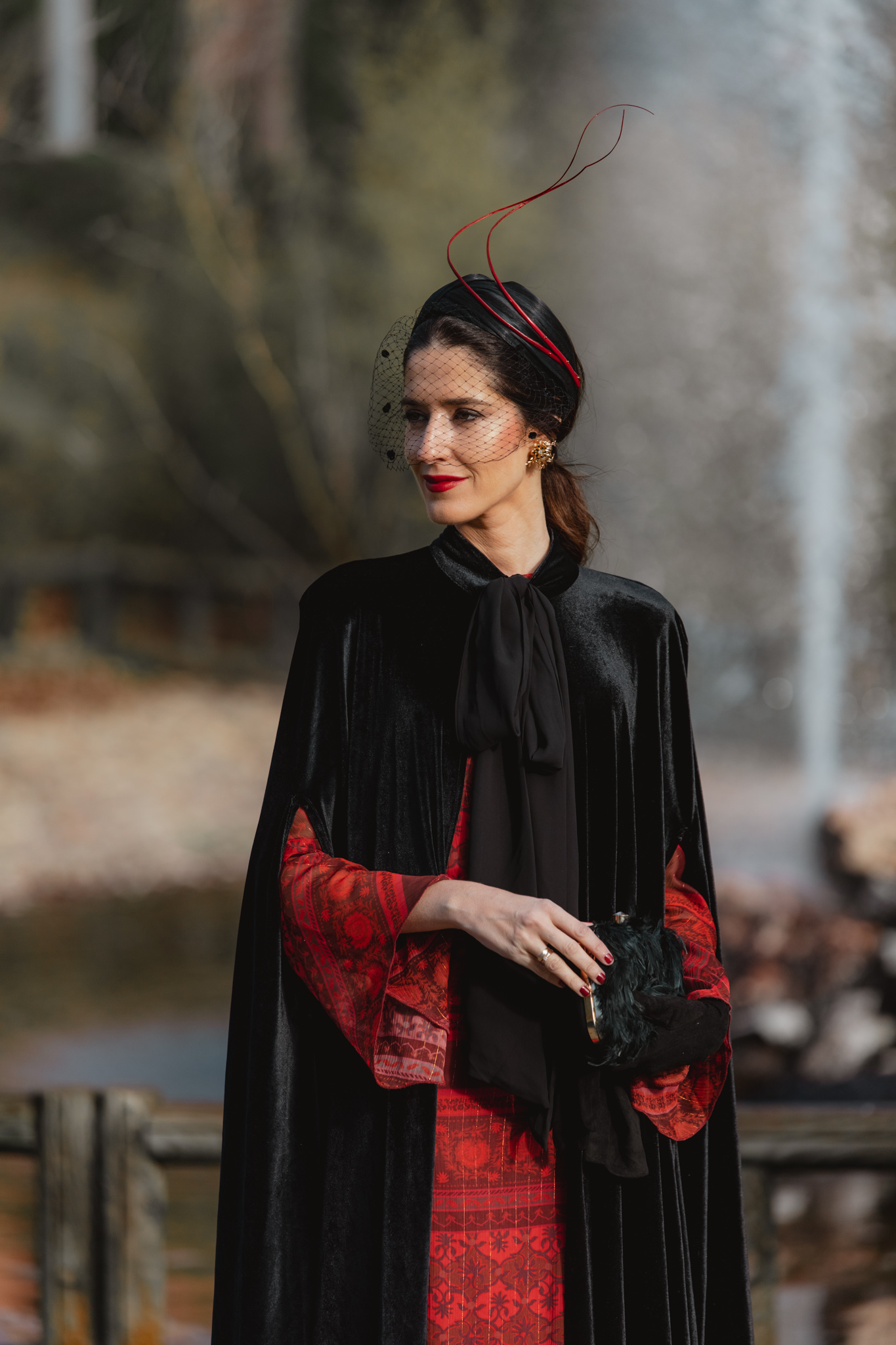 Look de invitada de invierno con vestido rojo y detalles granates y capa de terciopelo