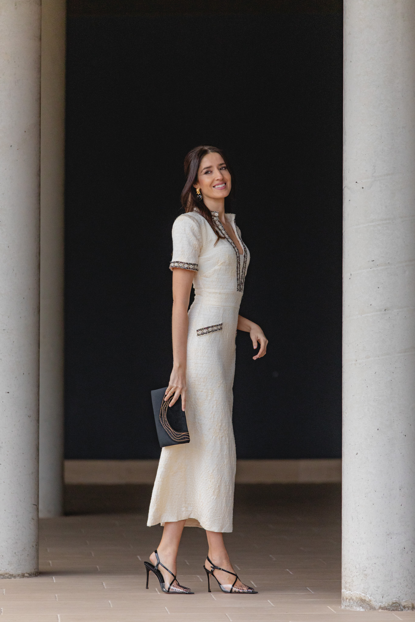 Plano general del estilismo con clutch negro y sandalias de tacón.