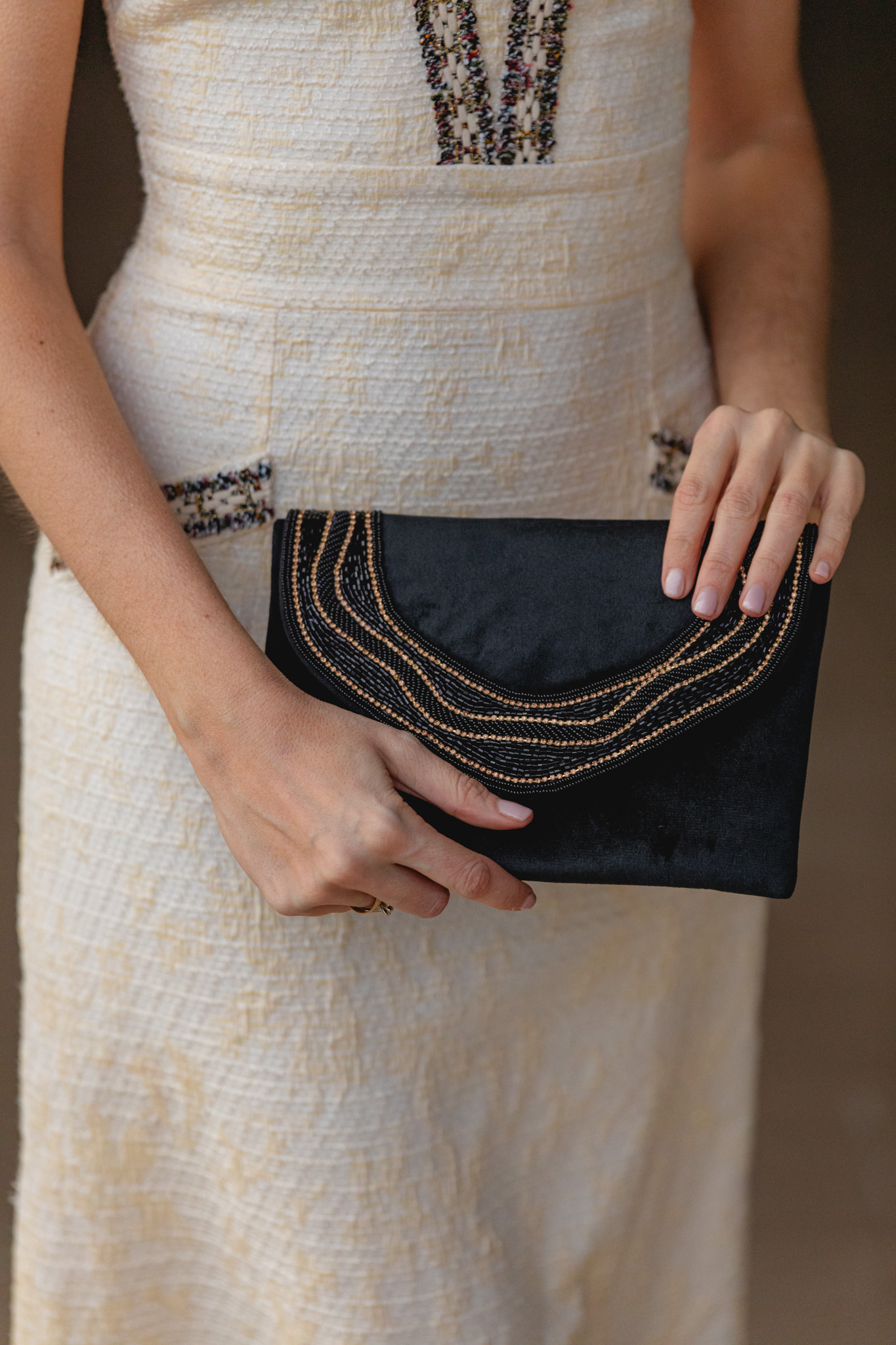 Clutch negro con aplicación dorada y textura artesanal.