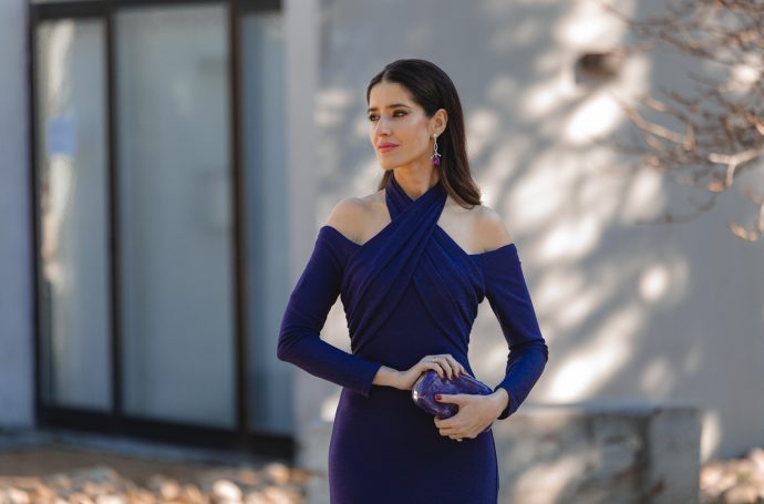 Vestido azul noche con manga larga y escote original en un look de invitada moderno.
