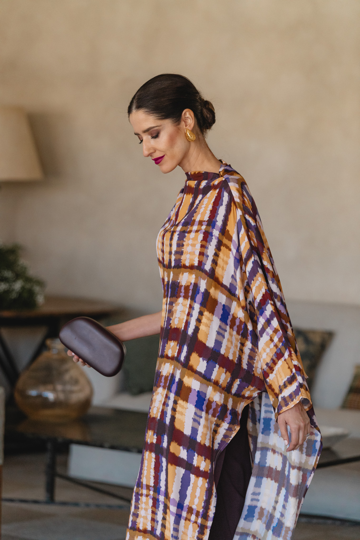 Invitada con túnica geométrica y pantalón berenjena en ambiente sofisticado
