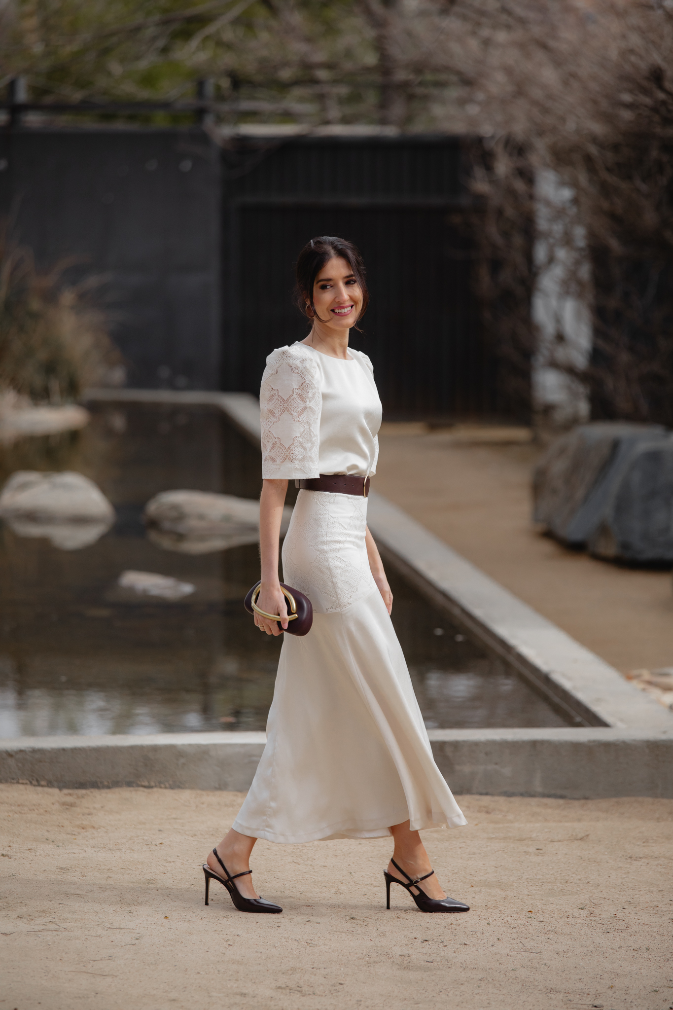 Mamá de comunión posando con conjunto marfil y clutch marrón