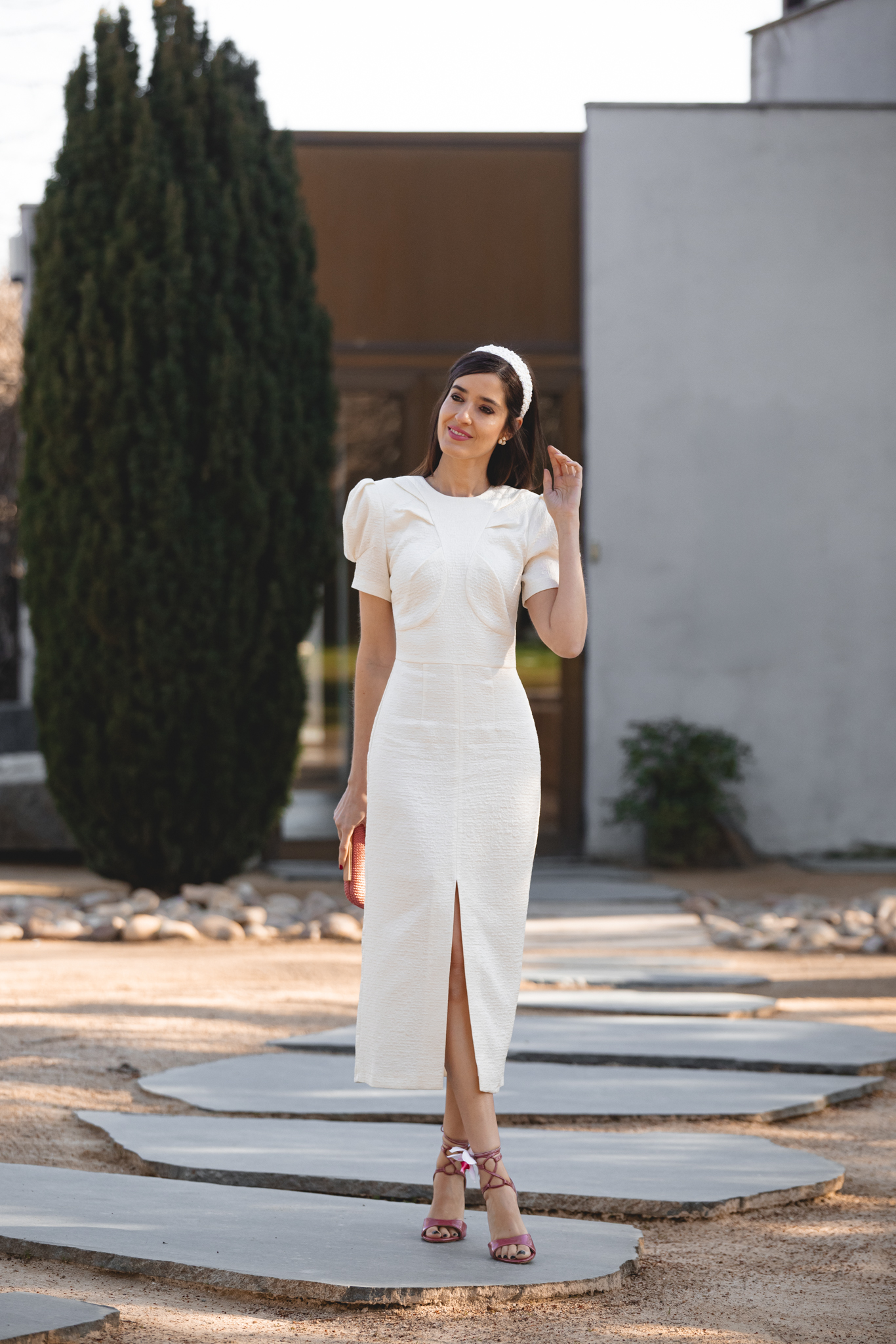 Invitada con vestido blanco roto y accesorios en rosa para comunión de día