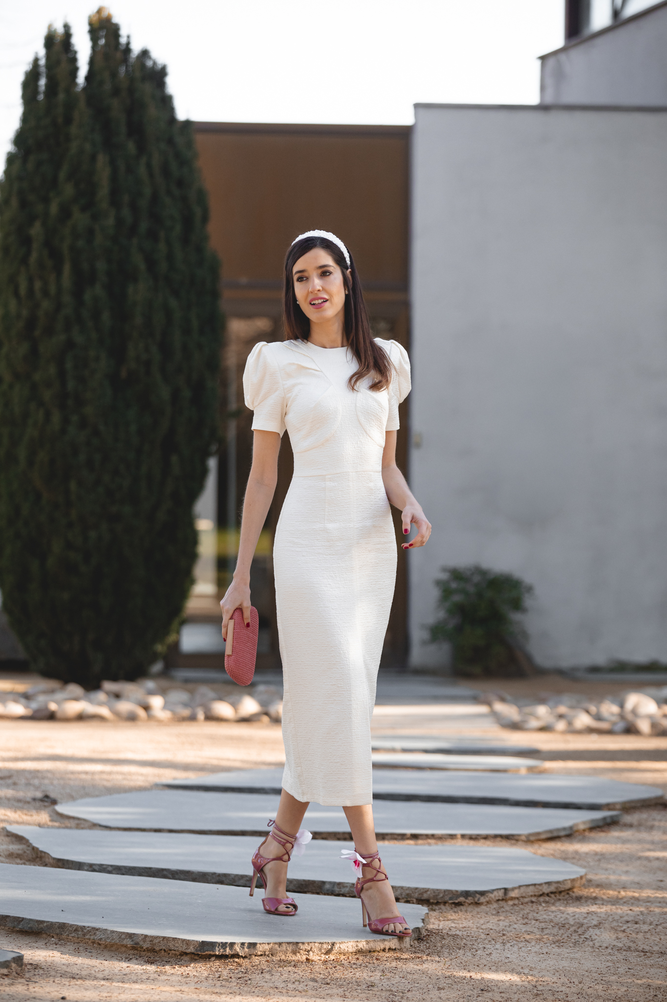 Vestido blanco roto con abertura frontal y diadema floral blanca en evento de día.