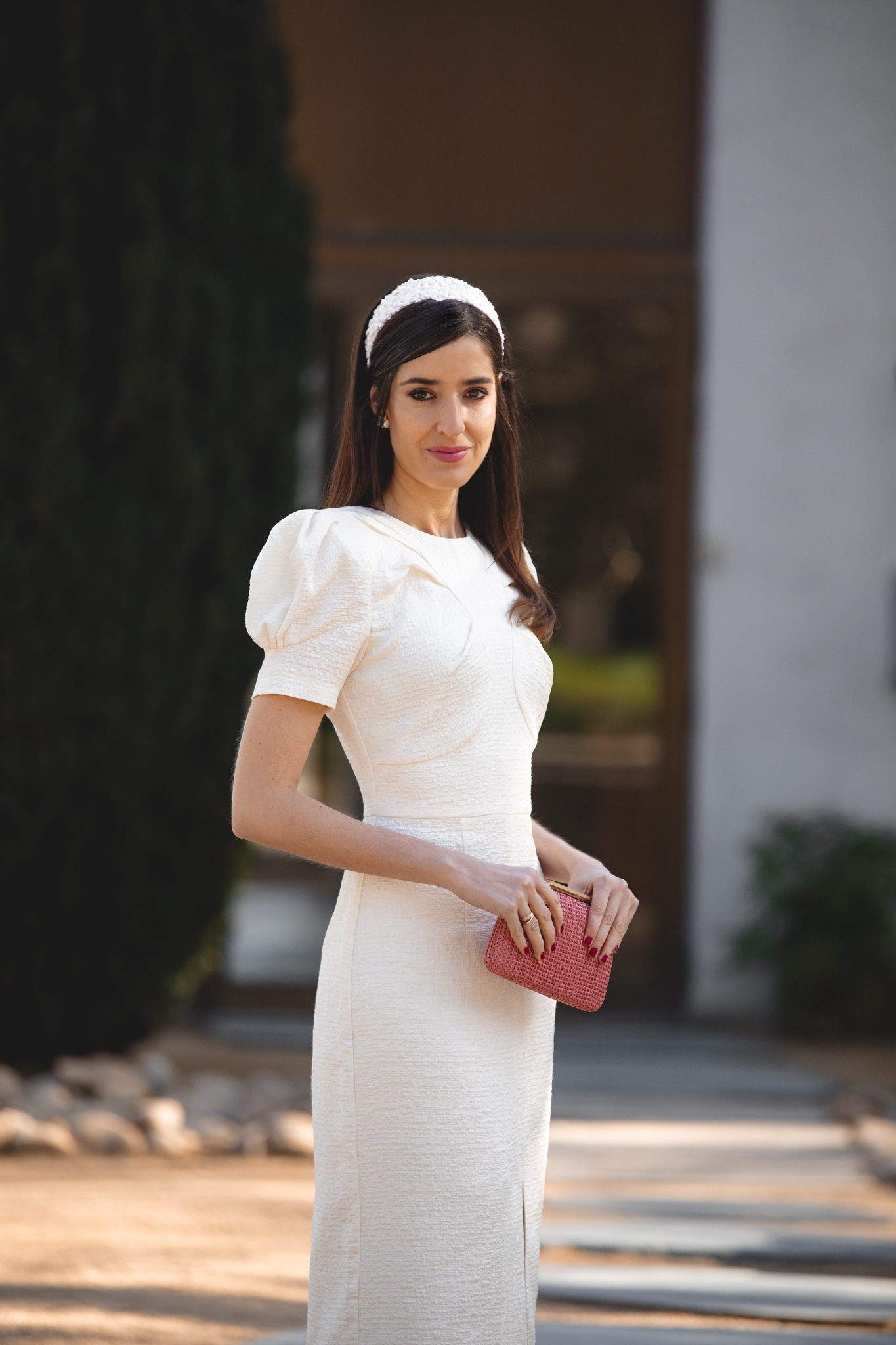 Vestido blanco roto de Meryfor con mangas farol y bolso rosa pastel.