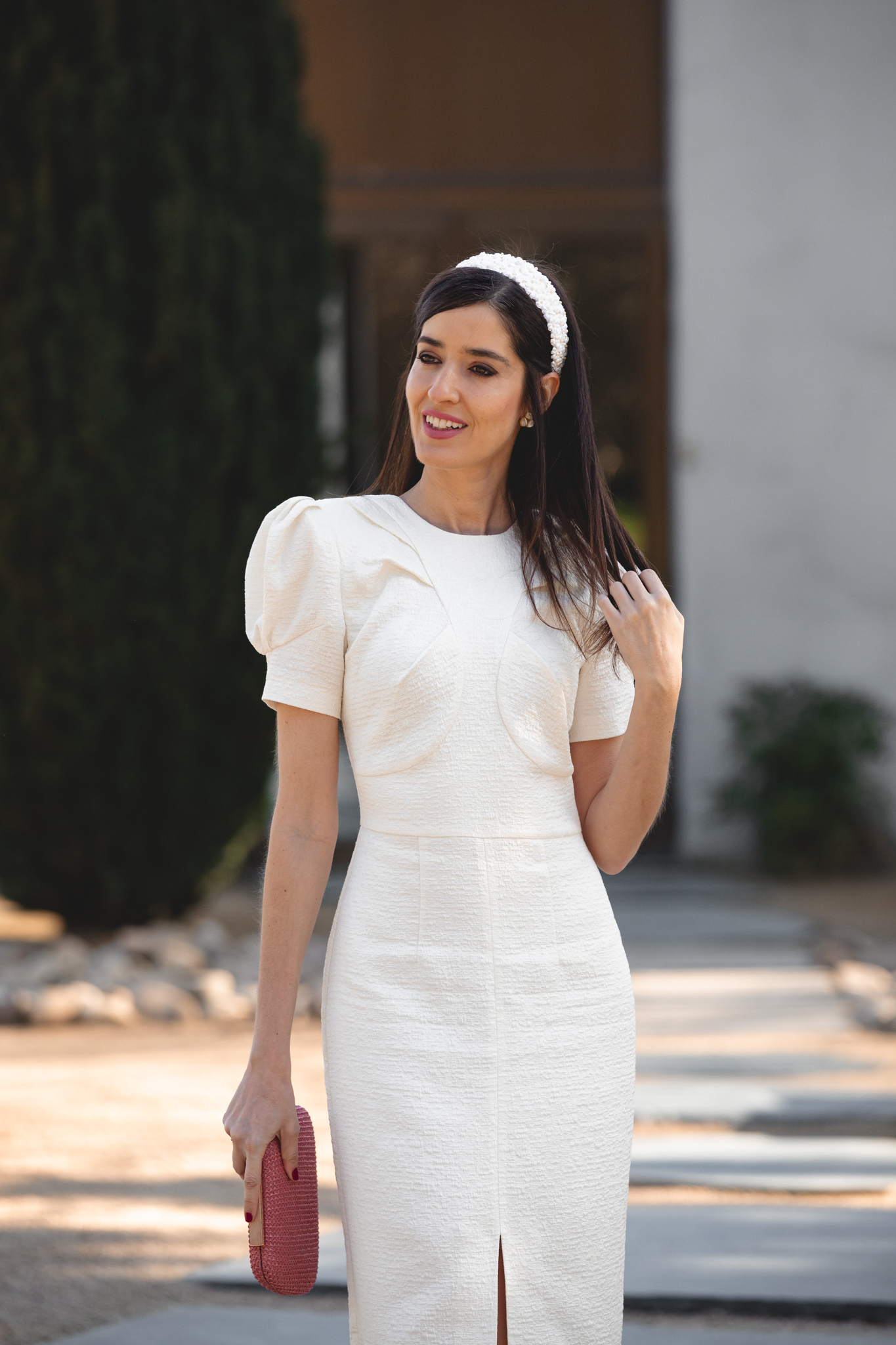 Mamá de comunión con vestido estructurado y diadema blanca en un entorno exterior.