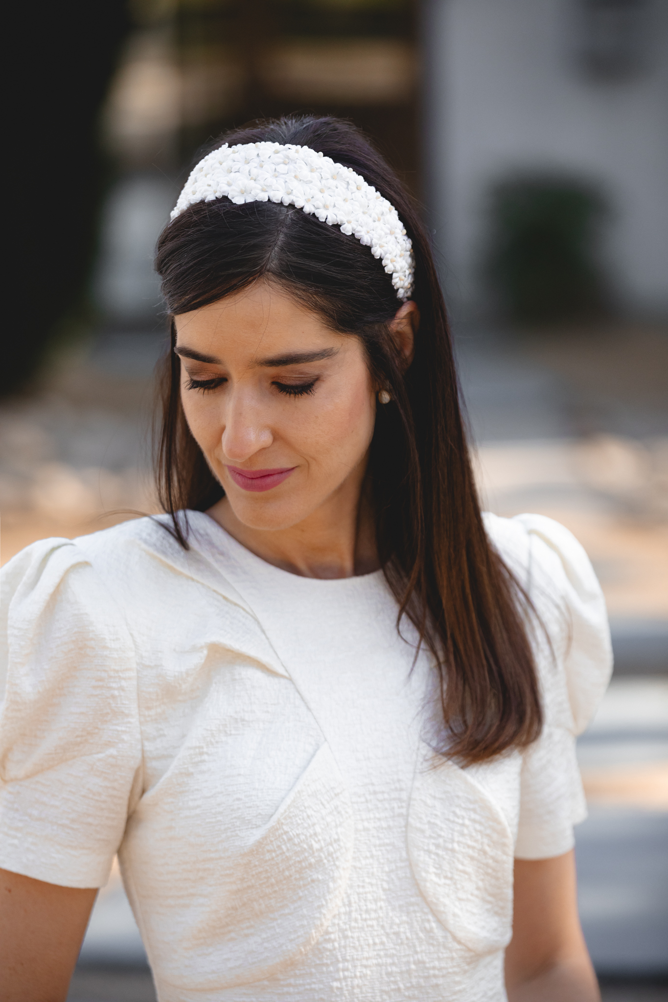 Diadema floral blanca combinada con vestido de comunión en blanco roto.