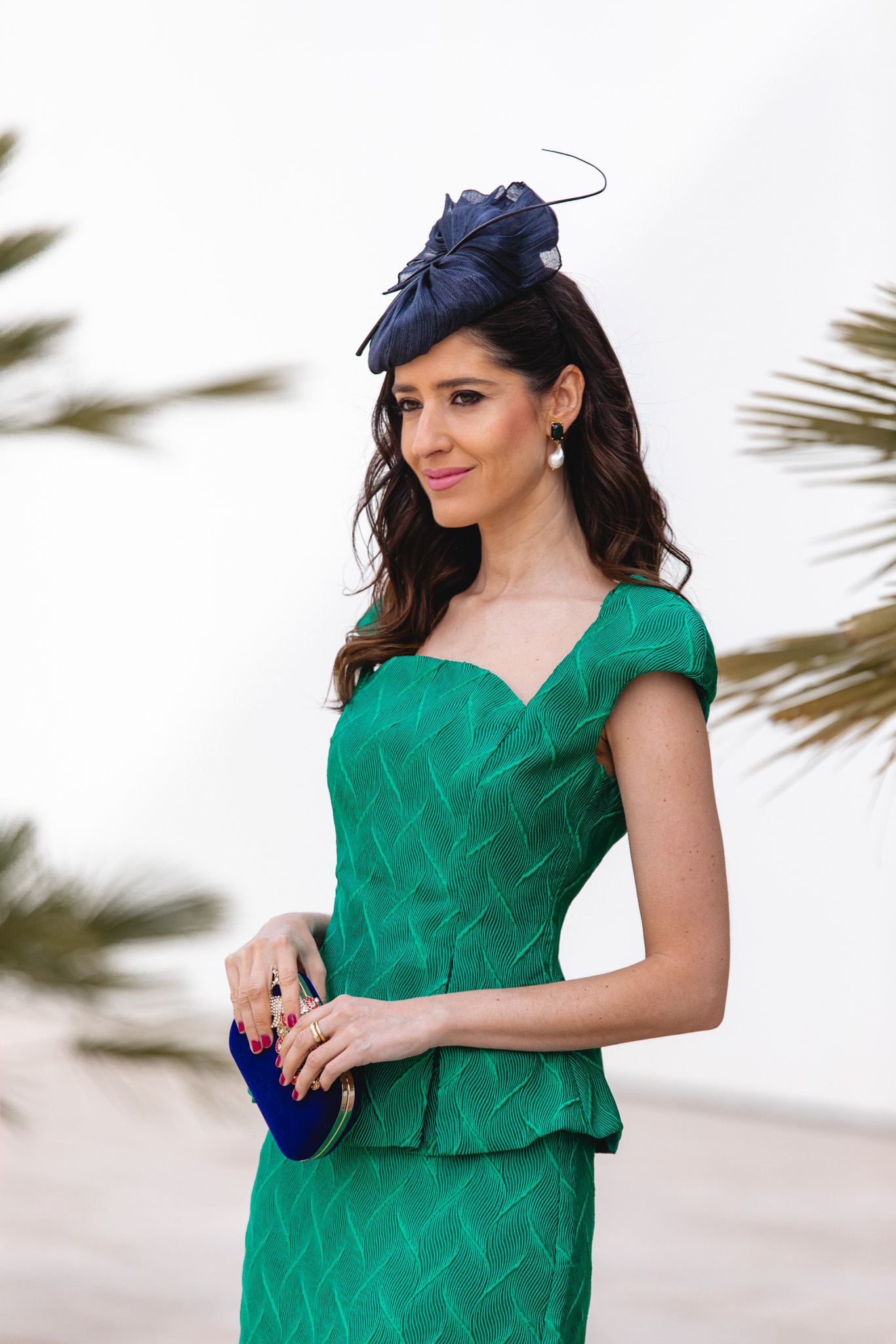 Conjunto verde esmeralda con peplum y tocado azul marino de estilo vintage.