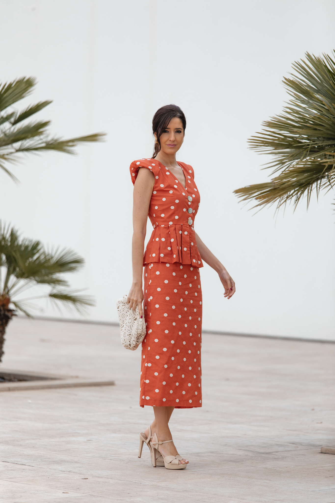 Conjunto de invitada en tono teja con lunares y accesorios en tonos beige y dorado.