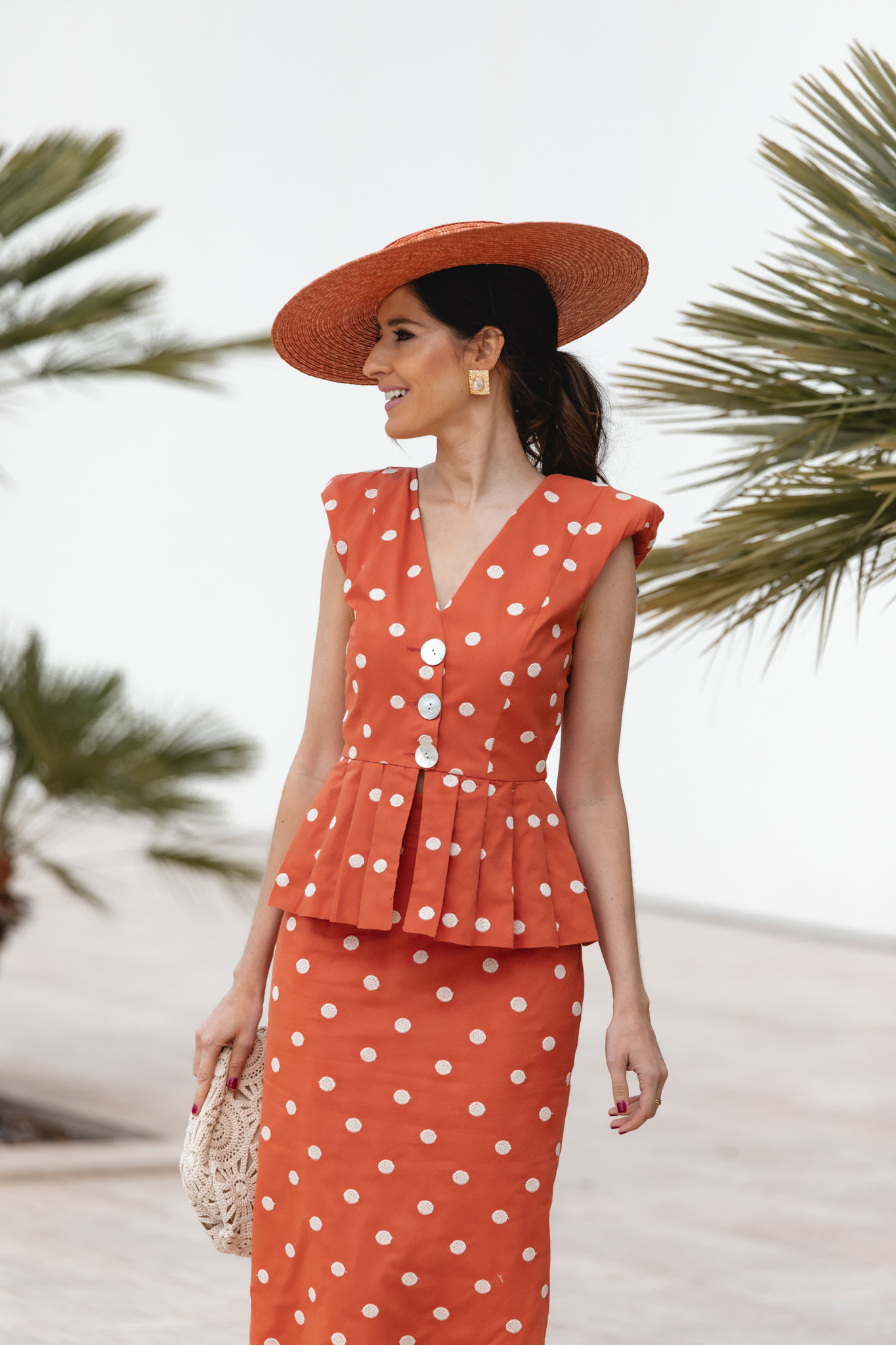 Look de invitada con pamela naranja y dos piezas de lunares en tonos cálidos.