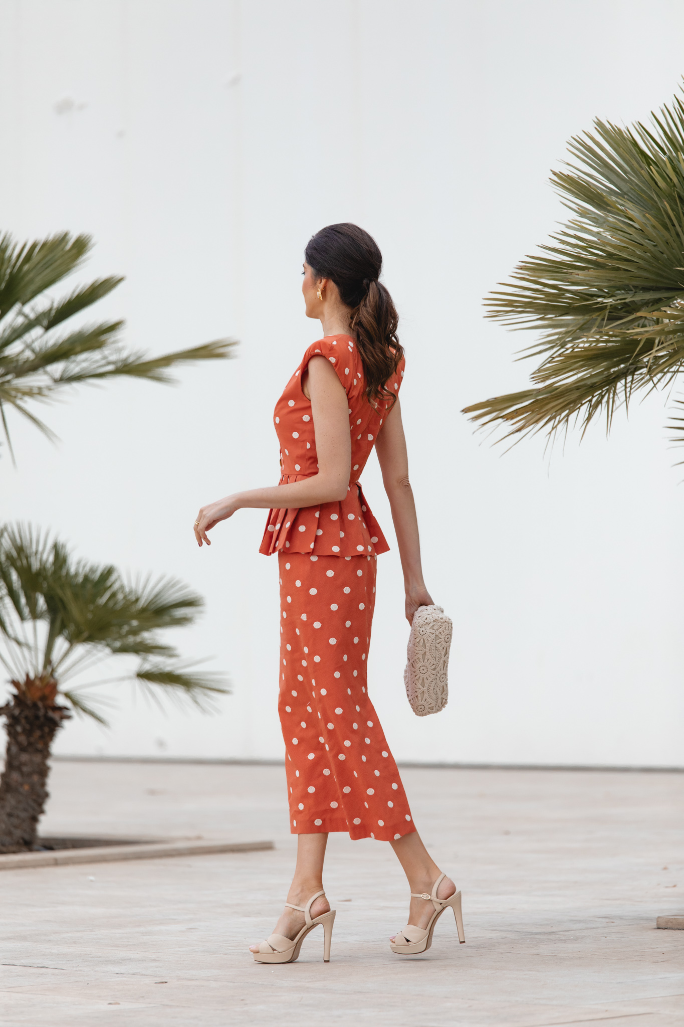 Look de invitada con falda midi teja y sandalias beige de tacón cómodo.