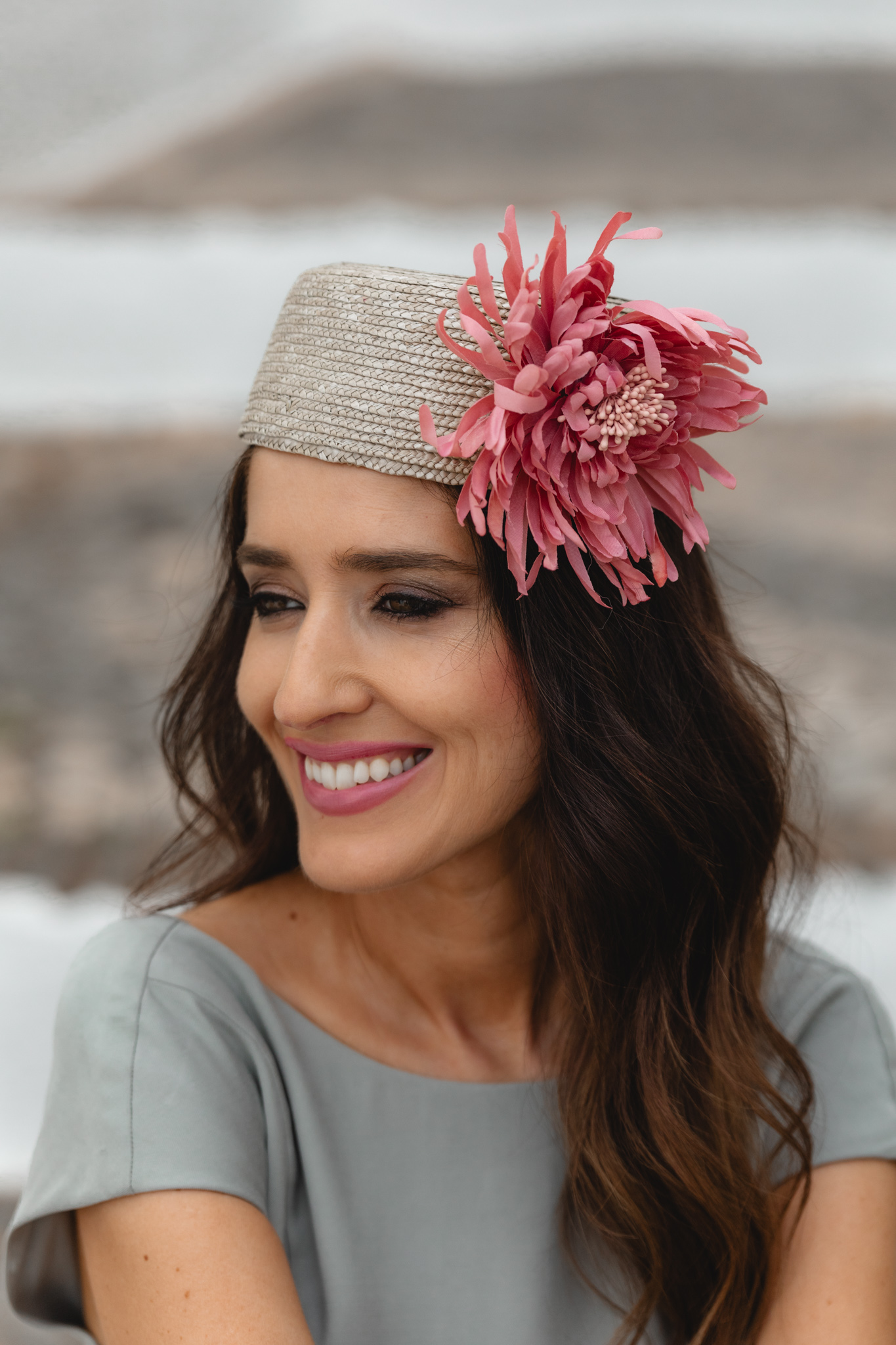Casquete de Masario con flor rosa sobre melena ondulada.