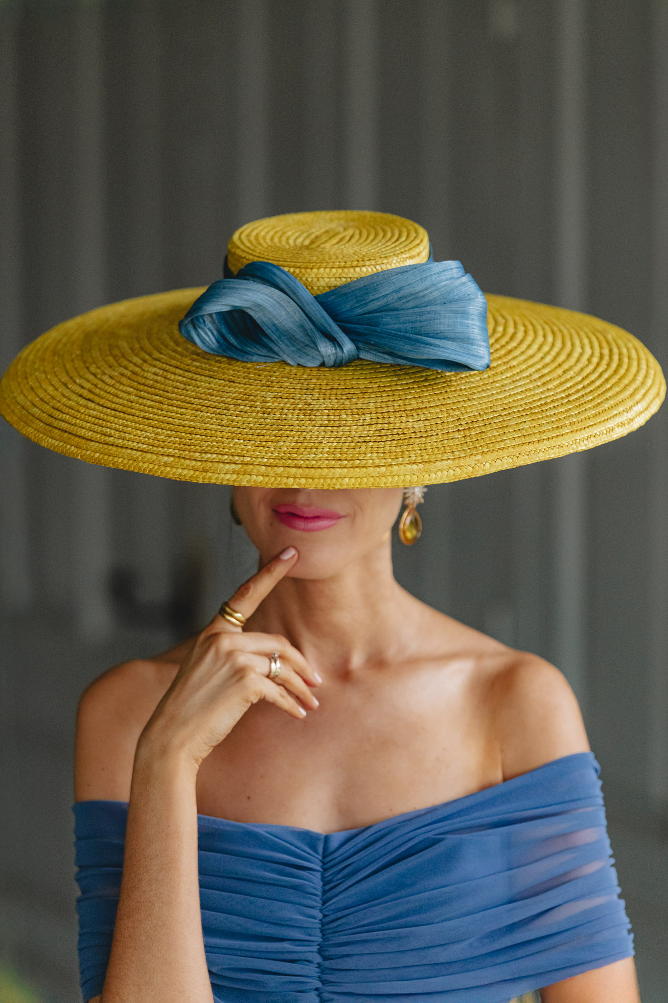 Detalle de pamela amarilla con lazada azul en look de invitada.