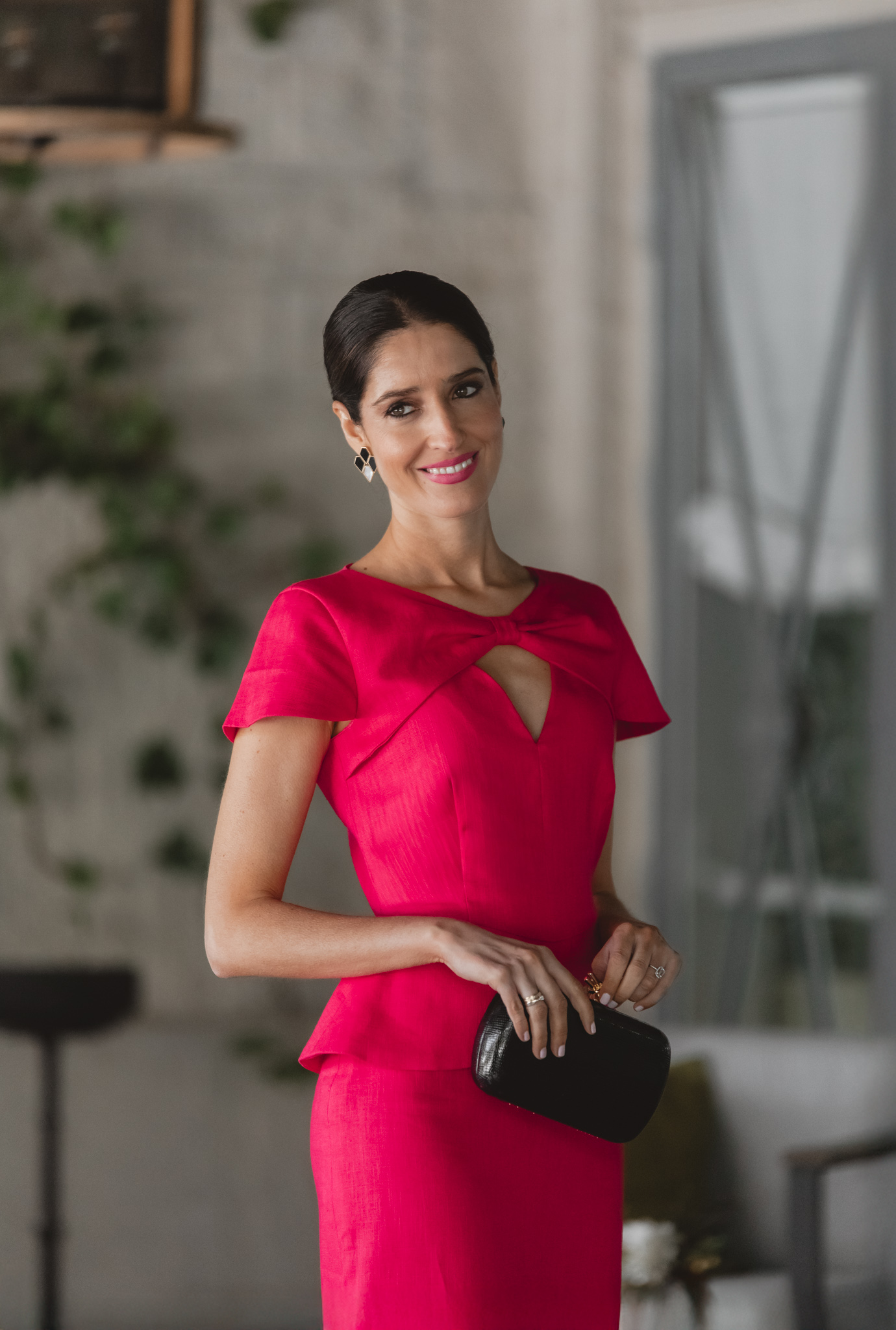 Sandra Majada con look de invitada en lino fresa y accesorios negros.