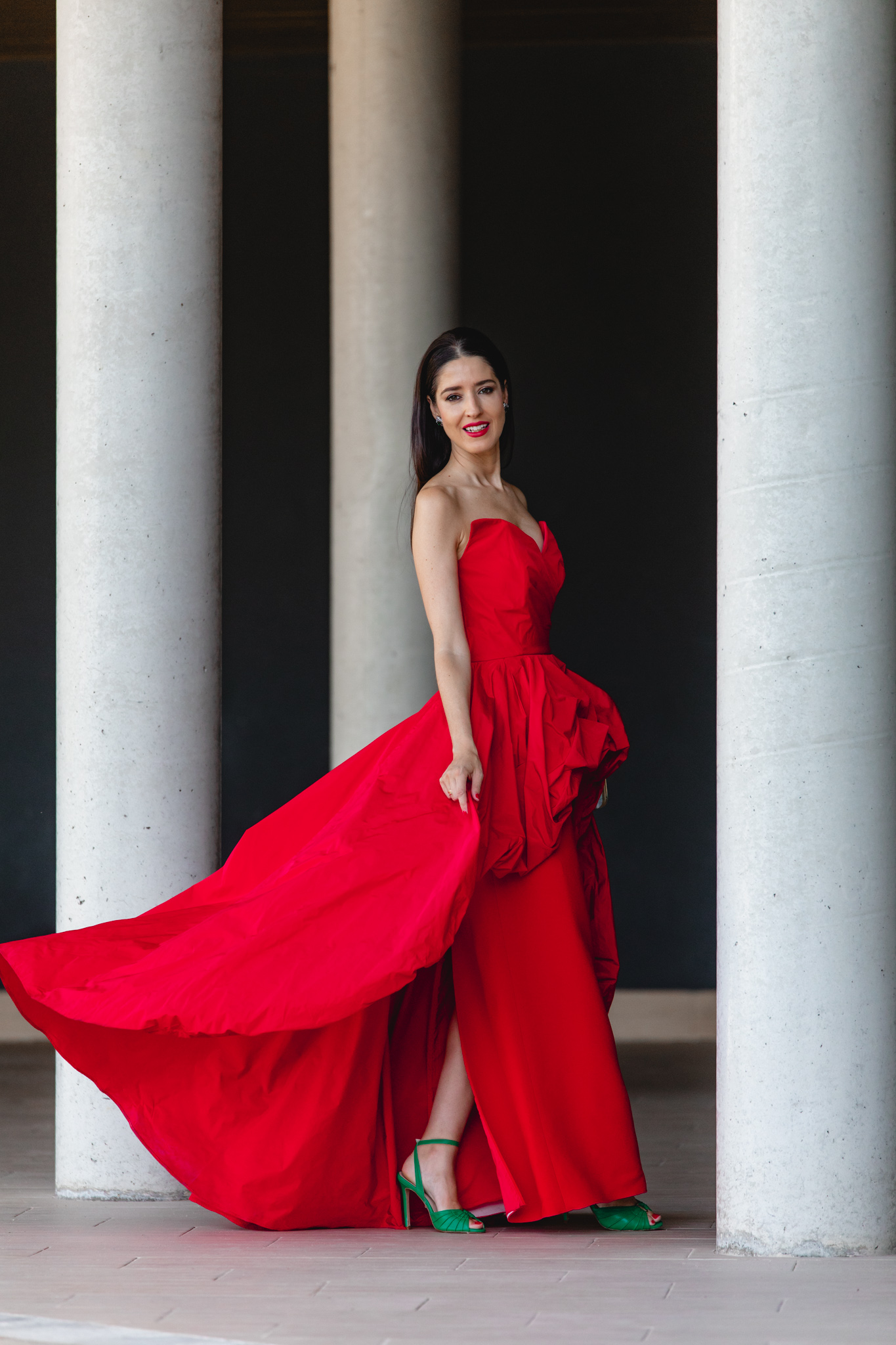 Vestido largo rojo de invitada con sobrefalda en vuelo y sandalias verdes de Salo Madrid
