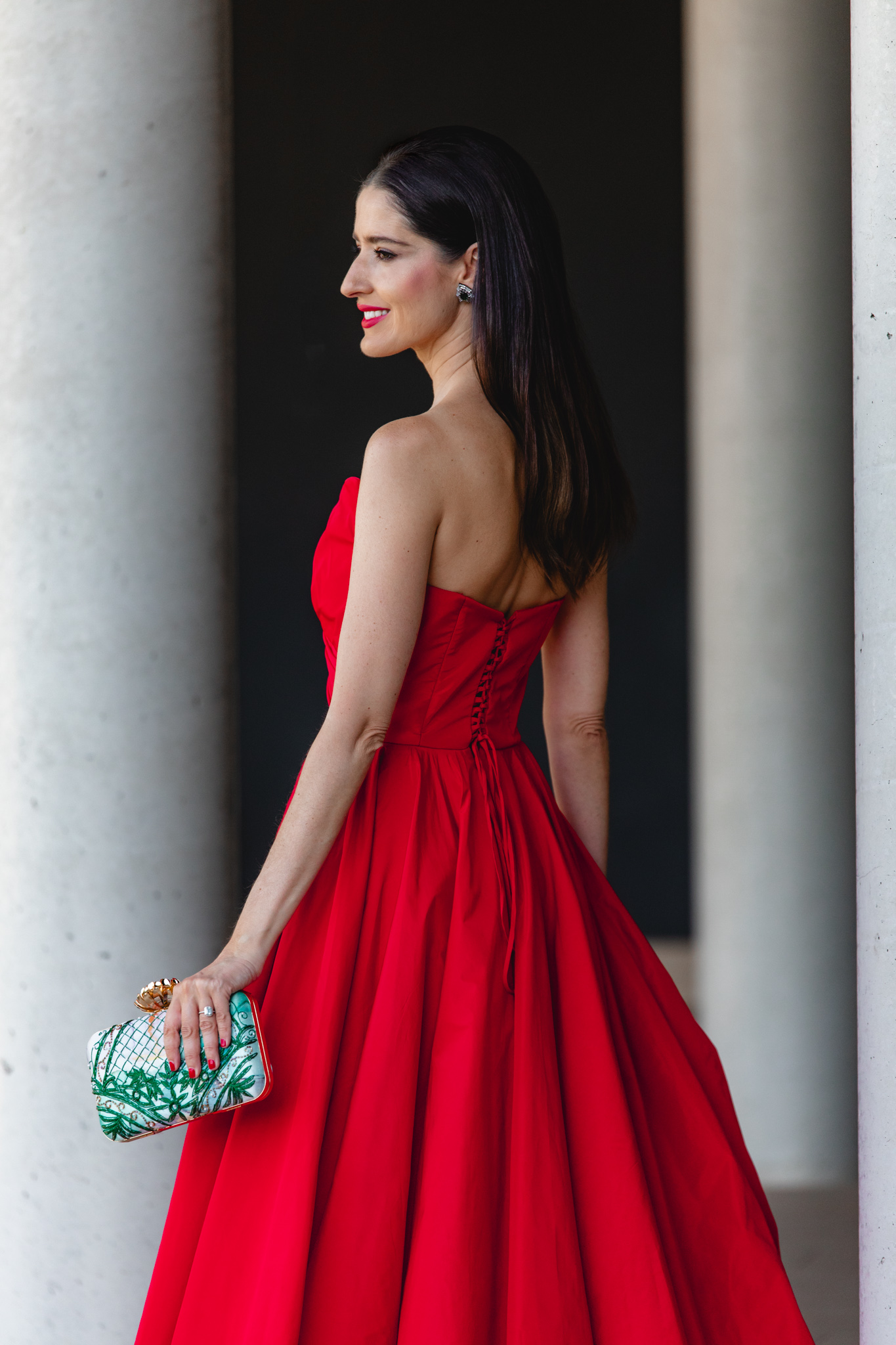 Vista lateral del vestido largo rojo con sobrefalda peplum y sandalias verdes de Salo Madrid