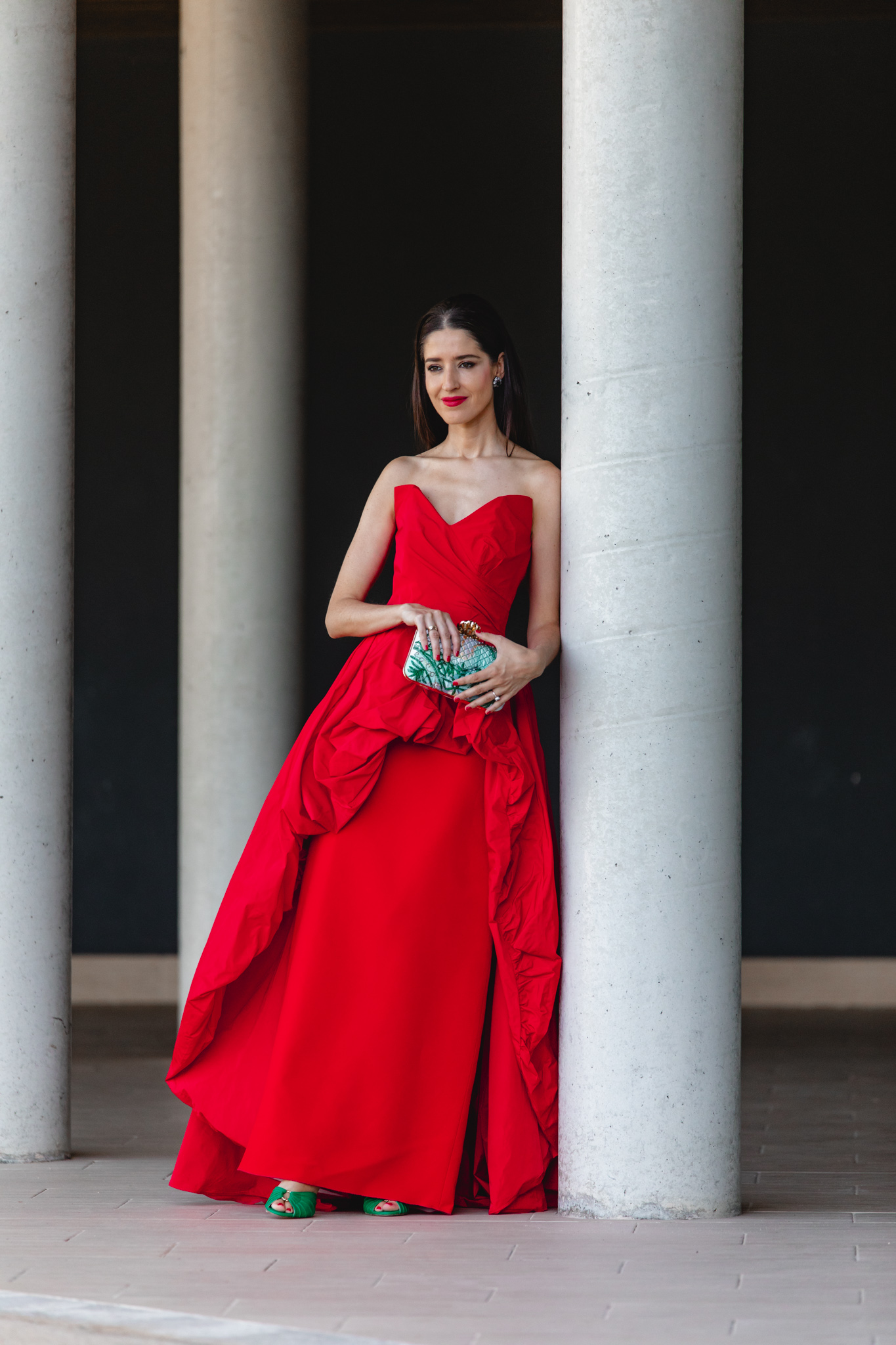 Vestido largo rojo de invitada con sobrefalda peplum y bolso verde estampado de Acus Complementos
