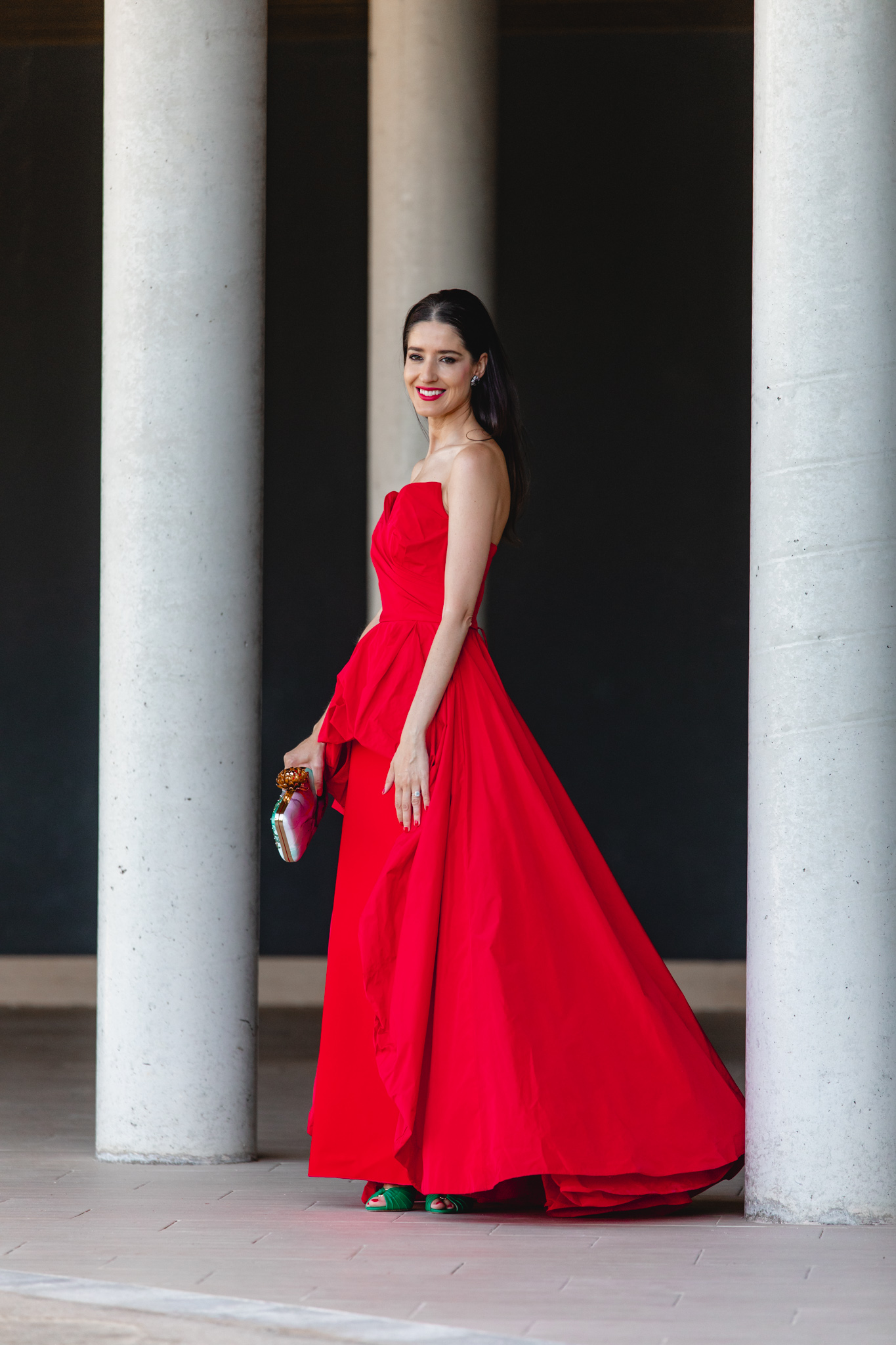 Look de invitada de boda de noche con vestido rojo largo y bolso estampado verde