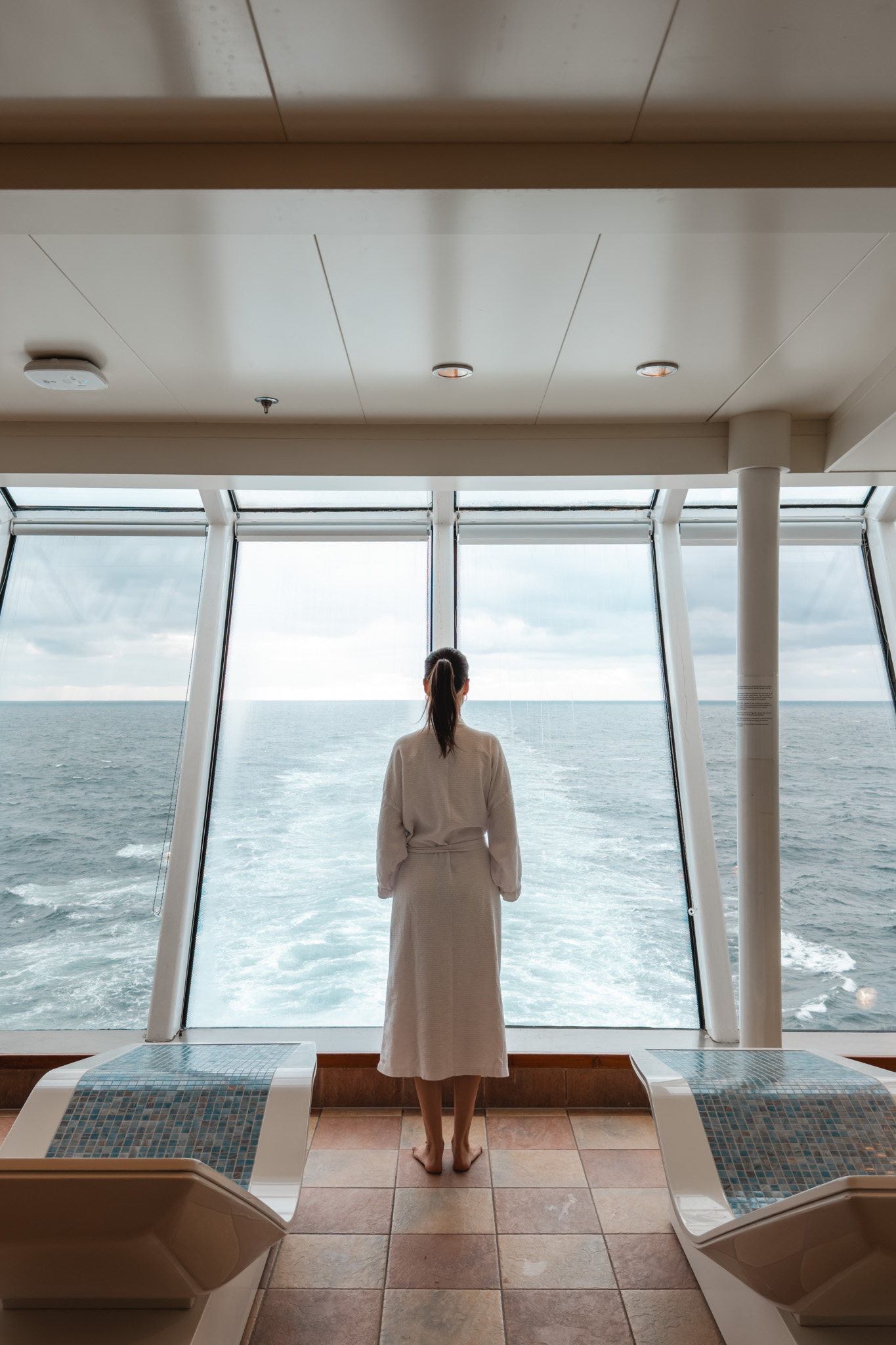 Mujer con albornoz frente al ventanal del spa del Norwegian Star