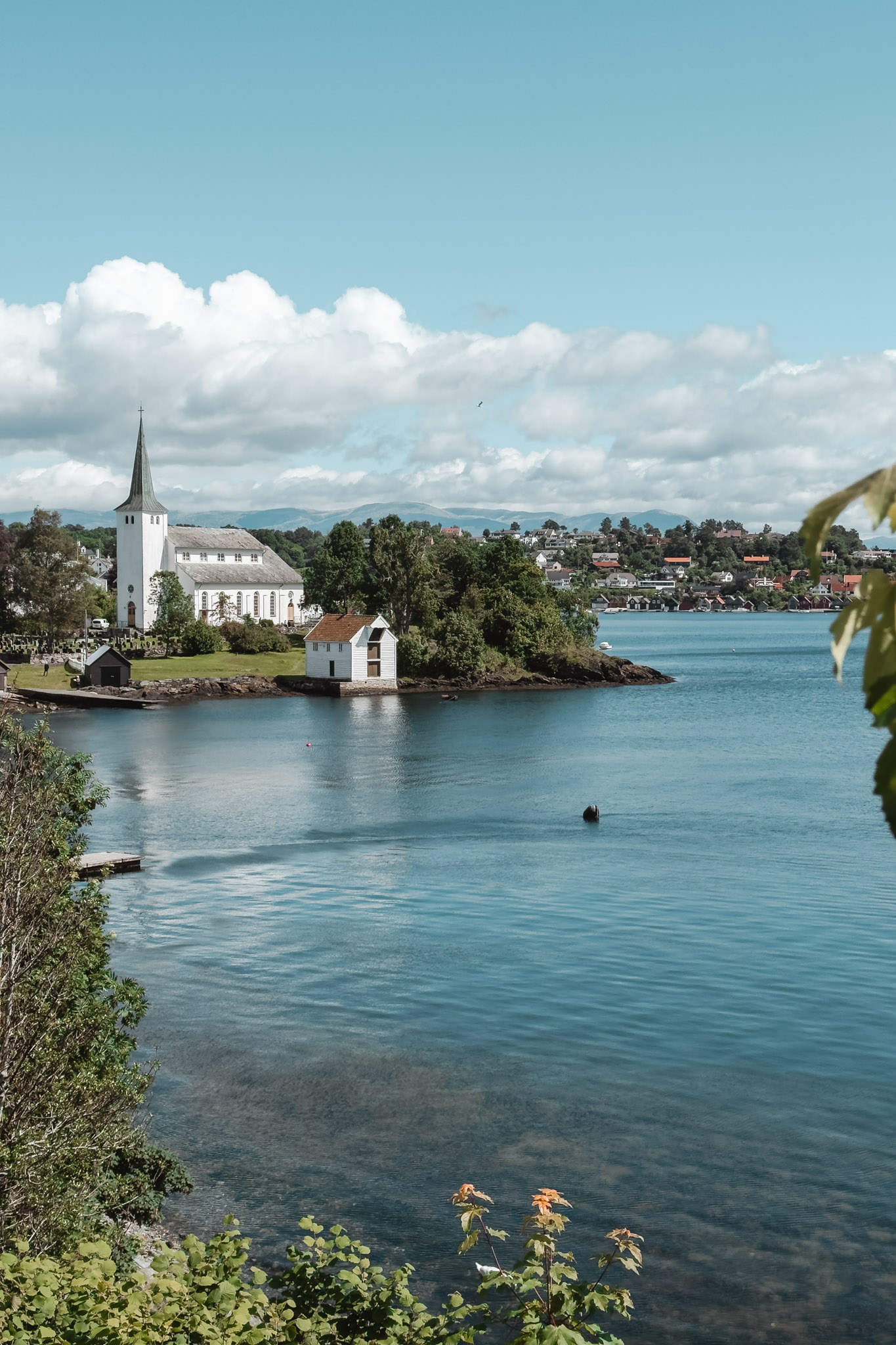 Iglesia blanca de madera junto al fiordo en Leirvik, Noruega