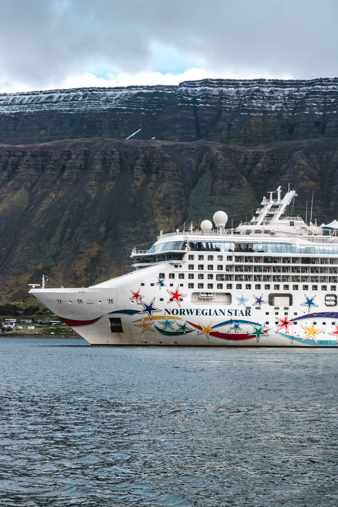 Crucero Norwegian Star atracado en un fiordo de Islandia con montañas nevadas al fondo