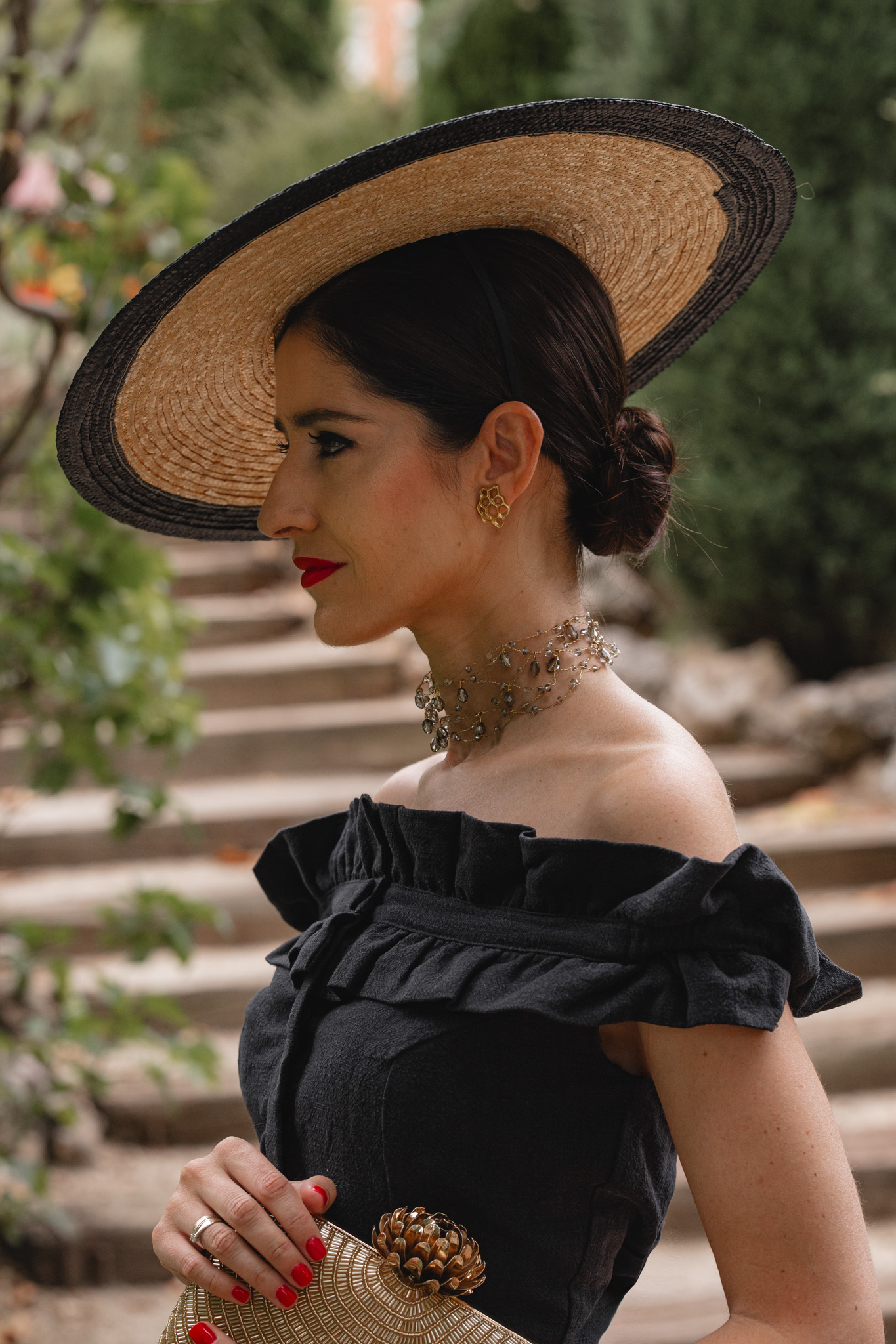 Retrato de perfil con pamela de rafia, gargantilla dorada y pendientes a juego