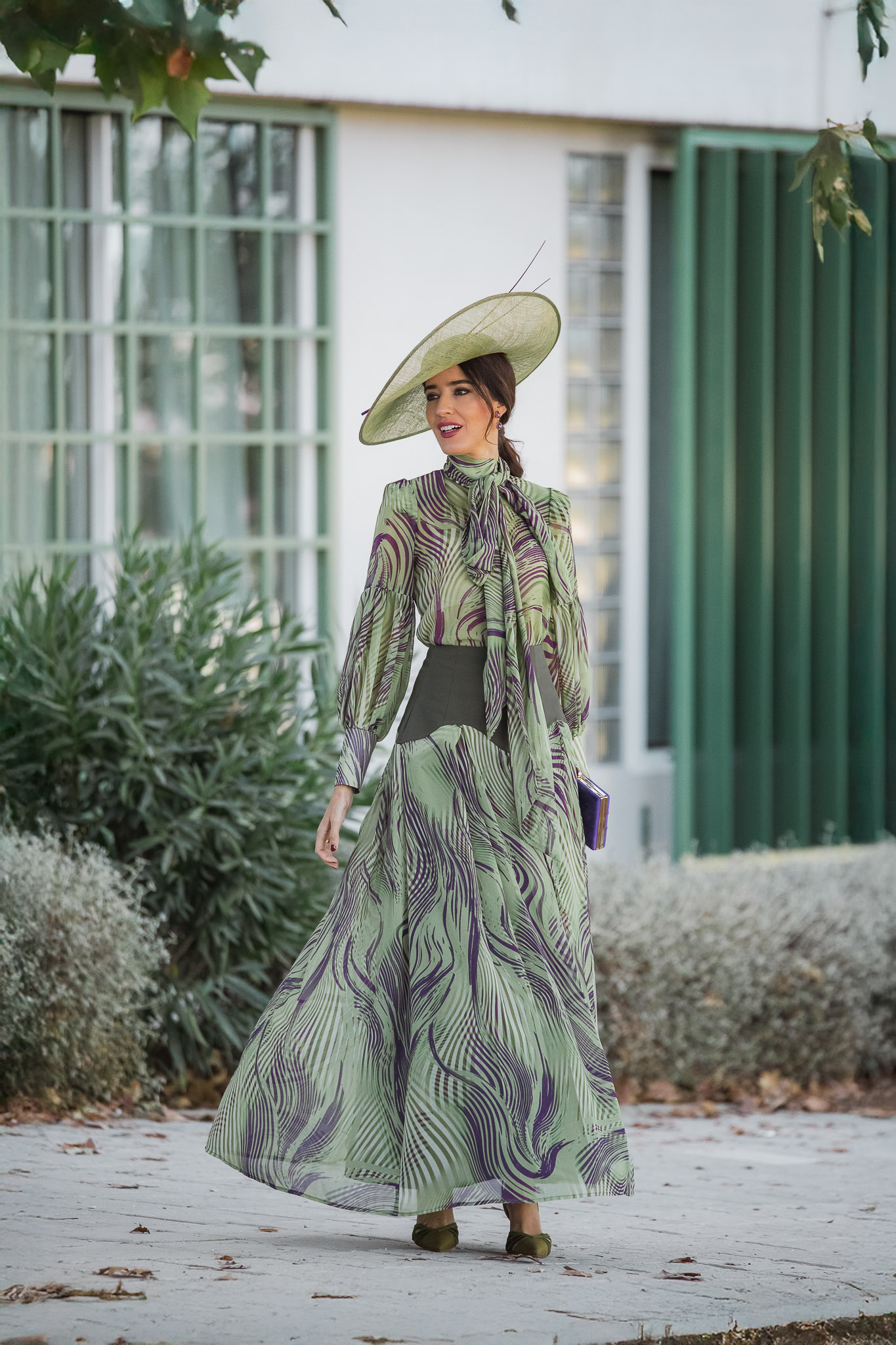 Invitada de otoño con conjunto de falda con vuelo y blusa verde Magnolia Kobus y pamela para boda de mañana