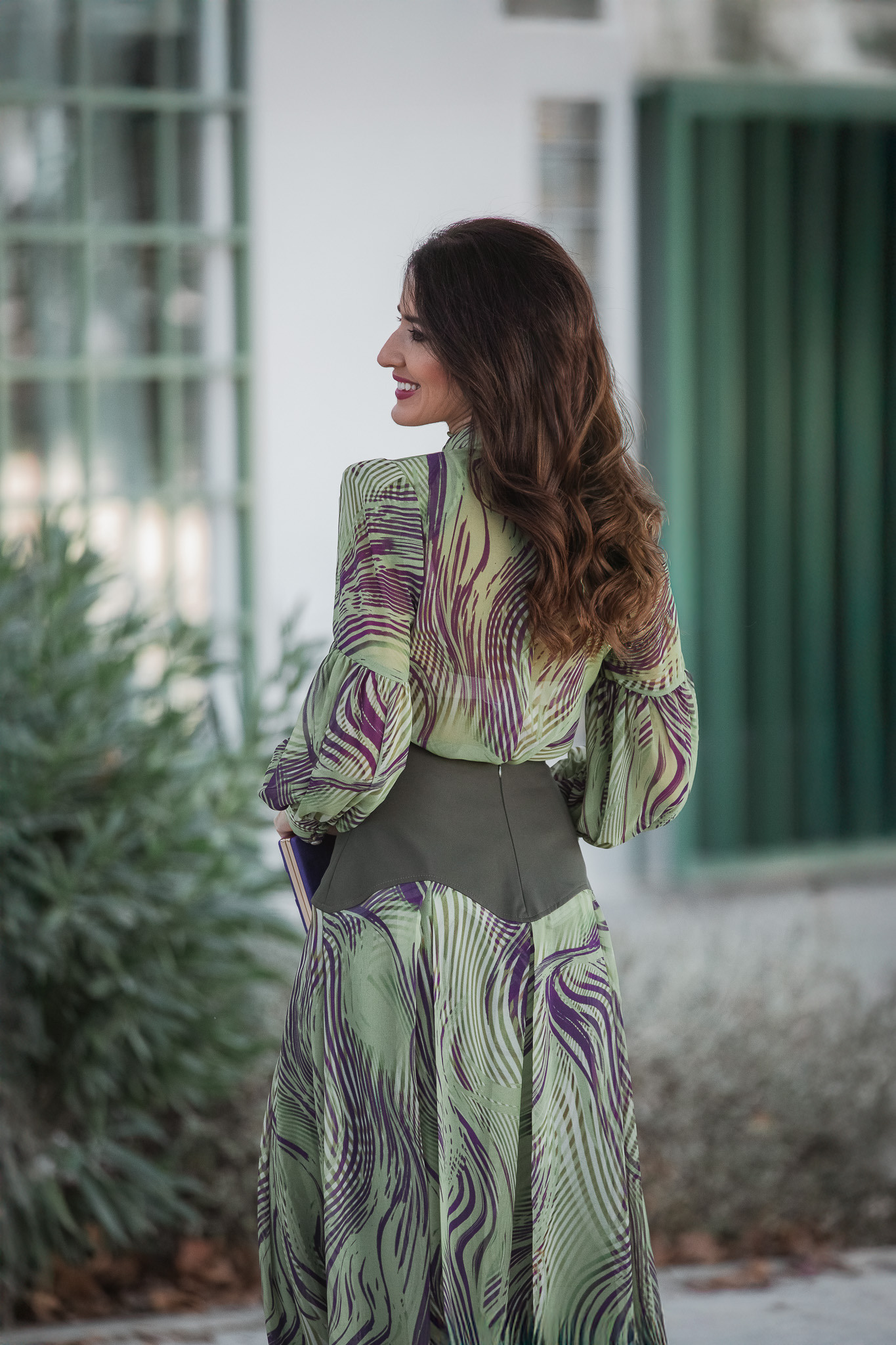 Espalda de la blusa verde con mangas abullonadas y falda Magnolia Kobus para invitada de otoño