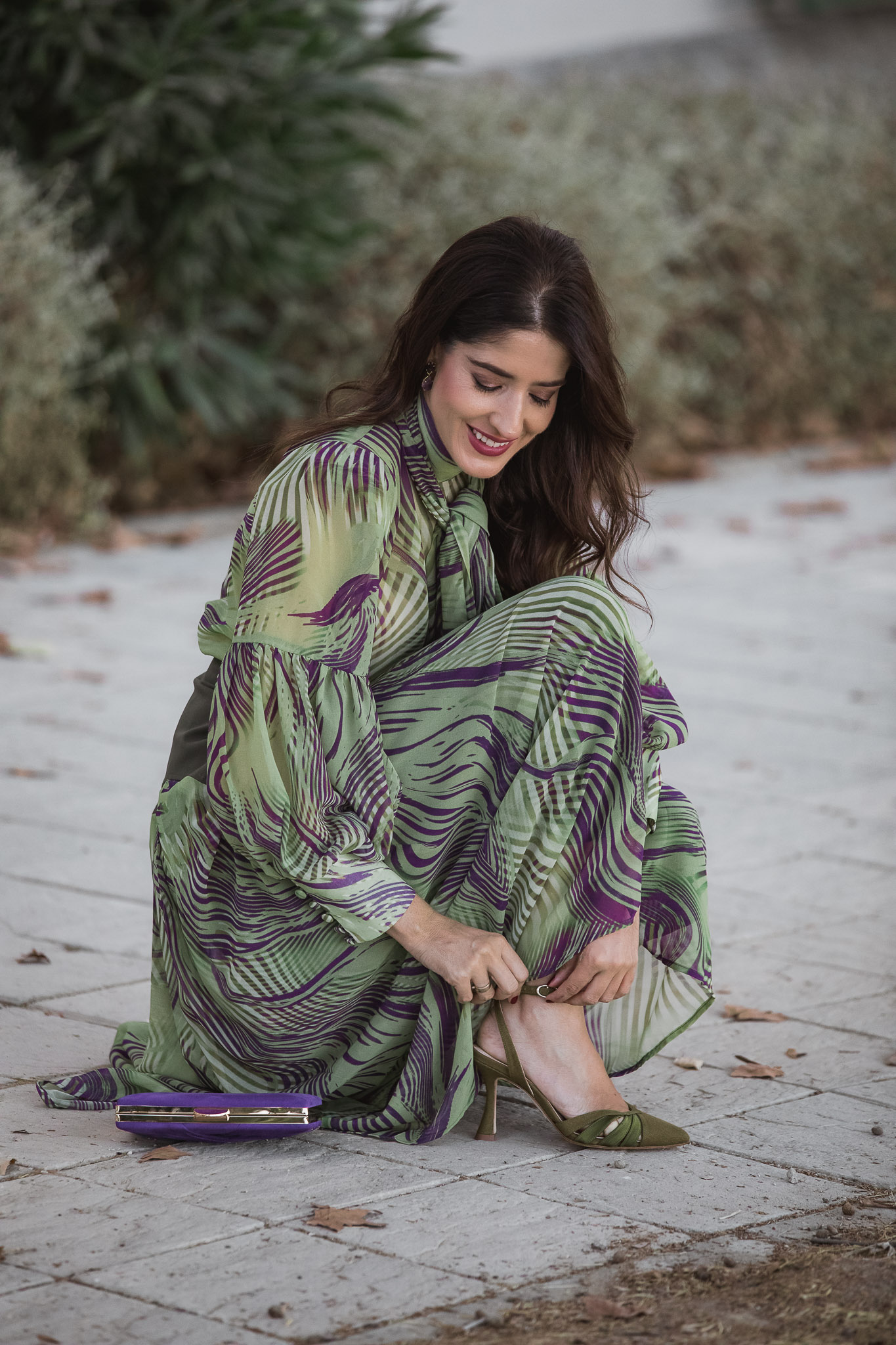 Invitada de otoño abrochando zapatos verdes Just Ene con conjunto Magnolia Kobus y bolso Occeanis