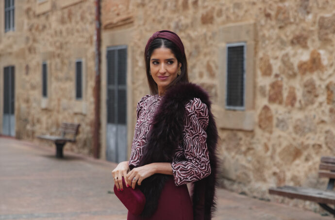 Sandra Majada, Invitada Perfecta, con diadema granate, estola y bolso de terciopelo burdeos